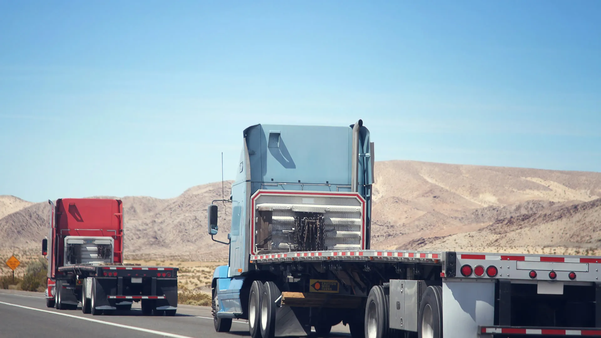 Two flatbed trucks on a highway